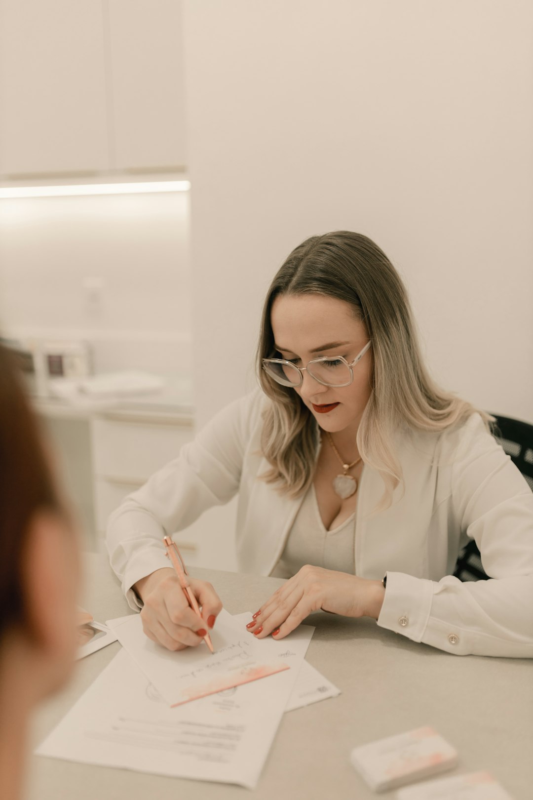 a-woman-sitting-at-a-table-writing-on-a-piece-of-paper-c3kssftxniw